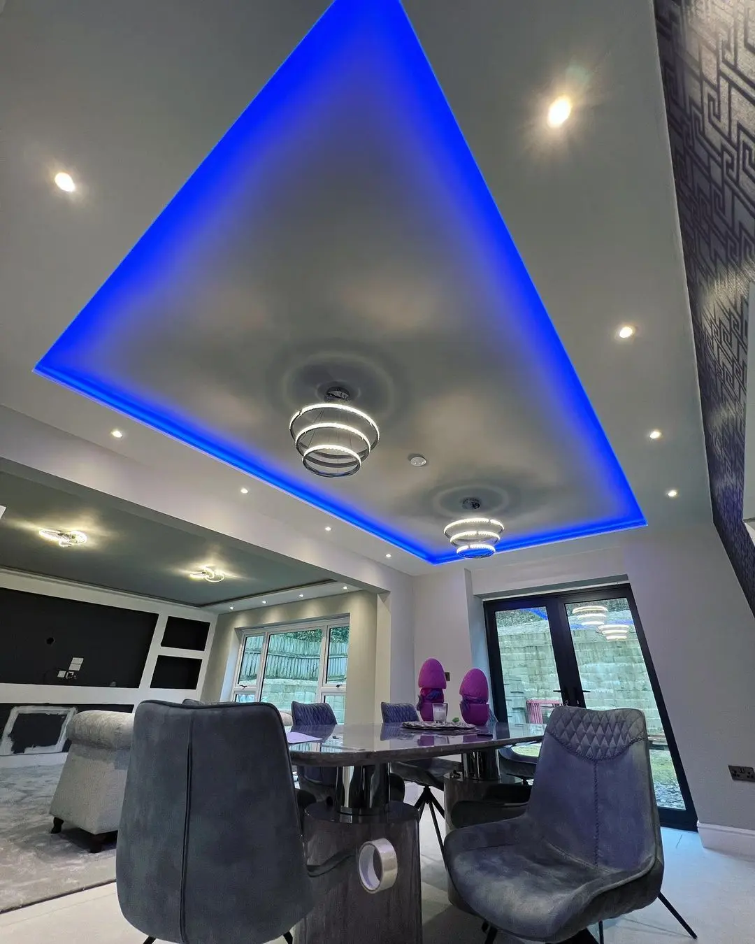 Contemporary open-plan living and dining room with blue LED ceiling lights