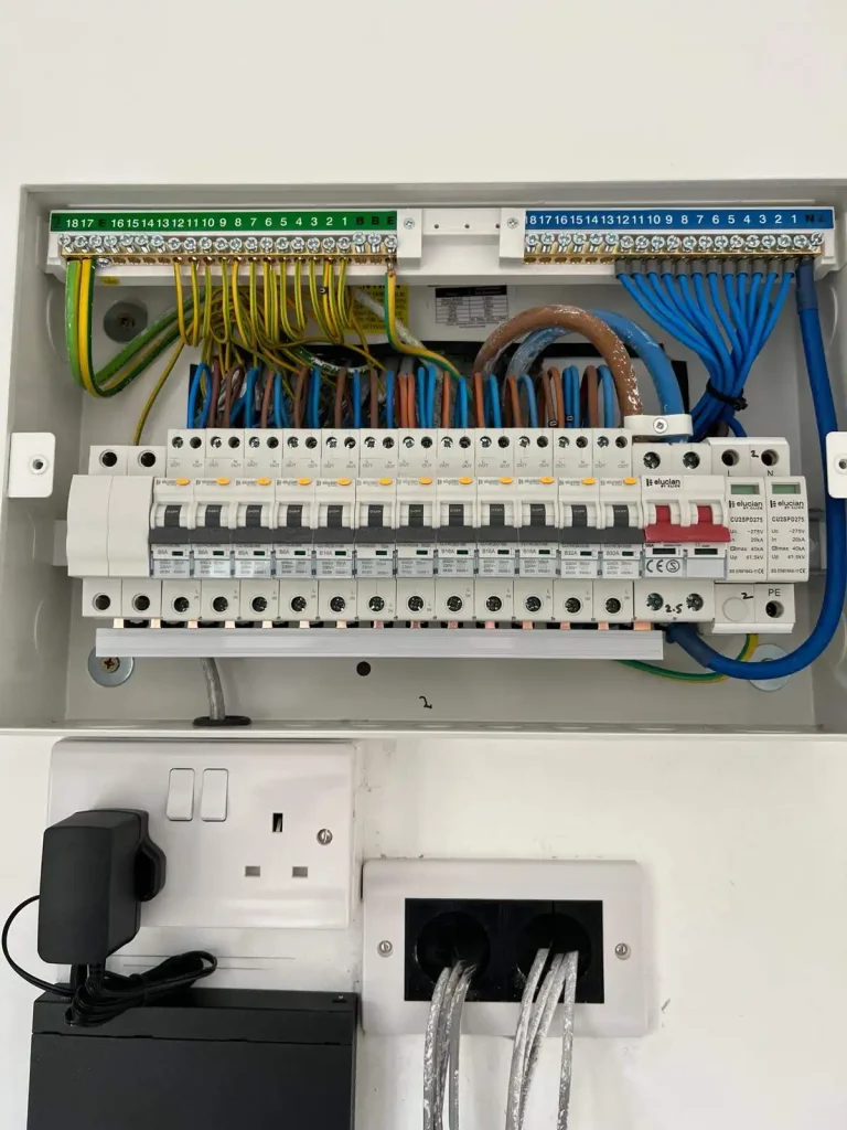 Electrical fuse box with labeled circuit breakers, colored wiring, and safety warnings about live terminals and fire risk