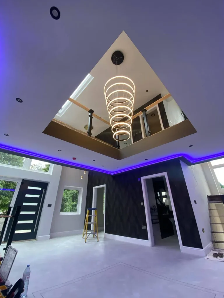 Modern interior with spiral chandelier, blue LED ceiling lights, recessed lighting, and high square cutout revealing upper level