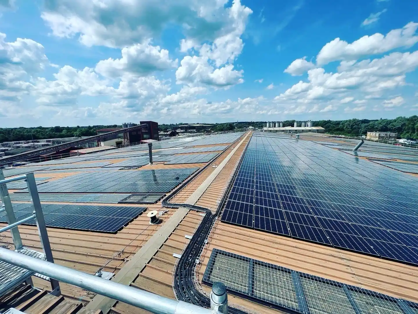 Extensive rooftop solar panel array arranged in rows under partly cloudy sky