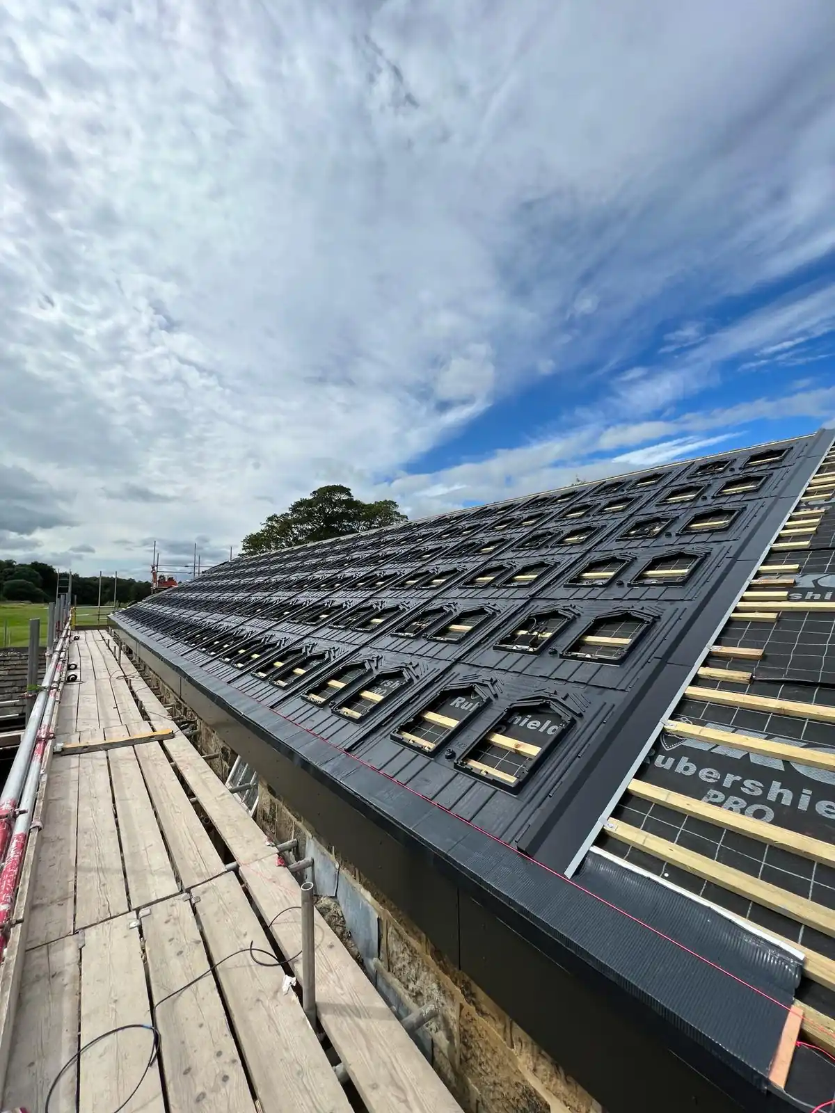 Building with scaffolding and rooftop covered in Rubershield PRO underlayment and wooden battens in preparation for solar panel installation