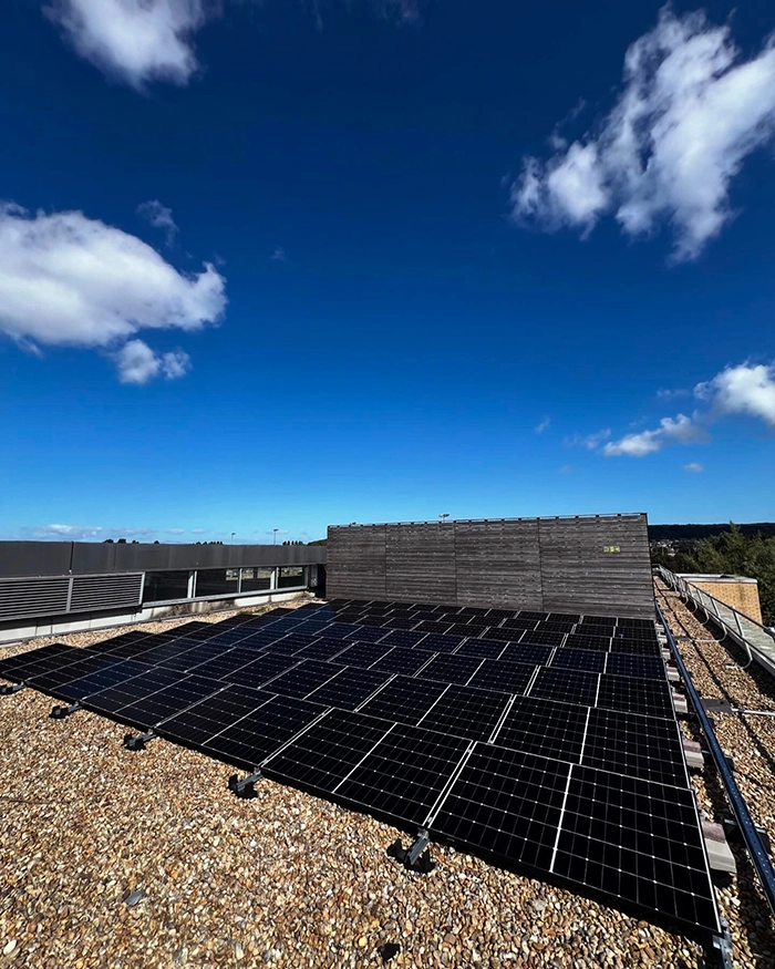 Grid of solar panels installed on rooftop under partly cloudy sky